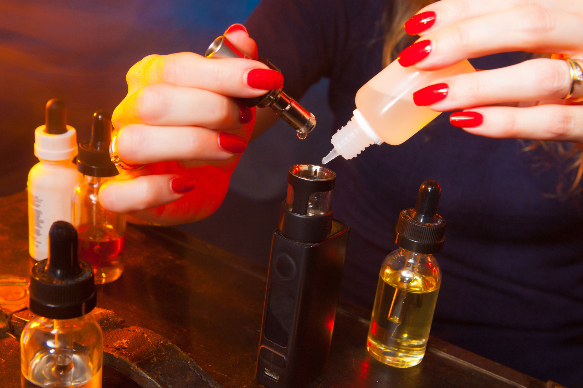The girl is running a liquid with an electronic cigarette. Liquids for Vape.